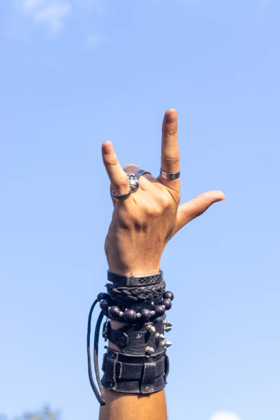 Man on rock with wristbands and with hand symbol