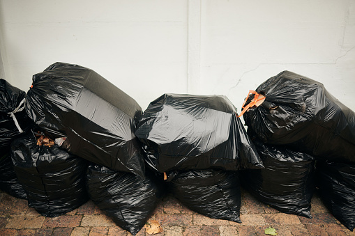 A stack of plastic garbage bags against a white wall. Copy space