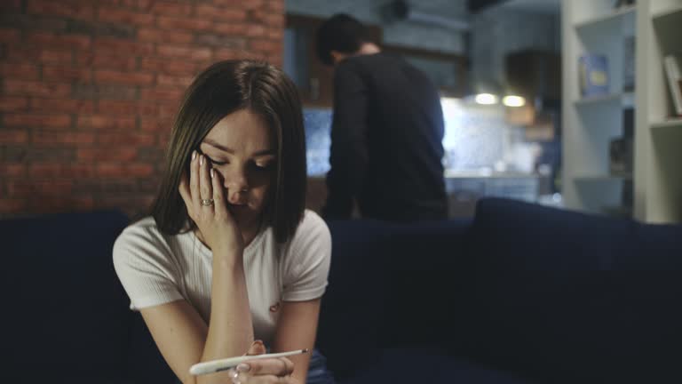 Caucasian lonely girl receiving positive medical pregnancy test. Close-up of sad worried young woman having problem, feeling depression, thinking of unwanted pregnancy. Concept of unwanted pregnancy.