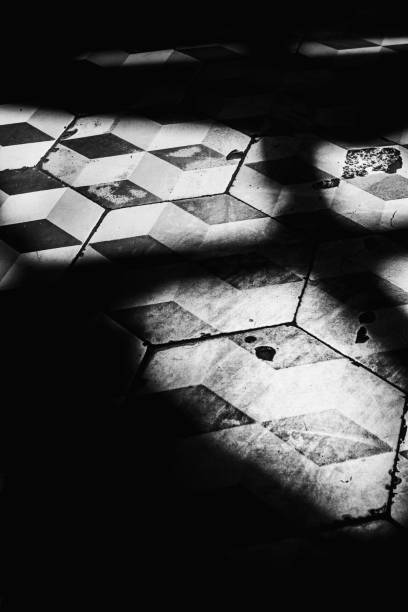 istock Vintage black and white diamond-shaped tile on a floor in an old cafe illuminated by yellow summer sunlight. Calm and mysterious summertime atmosphere. 2143580607