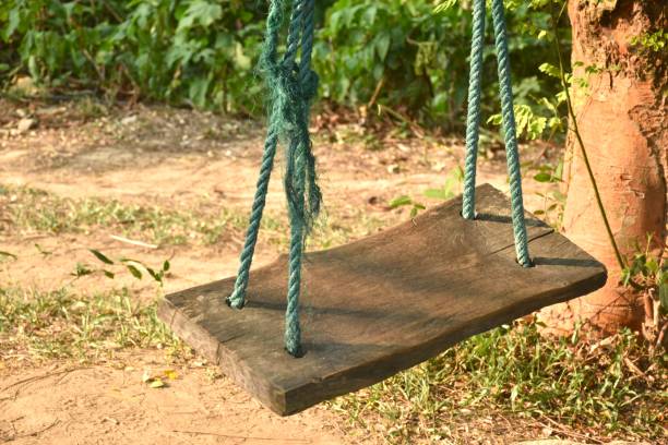 A wooden bench swing at a park offers a peaceful spot to relax and enjoy the outdoors