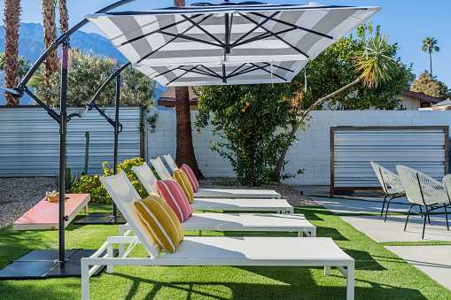 Backyard outdoor chaise lounge chairs with cantilever umbrellas and colorful pillows in Palm Springs, California