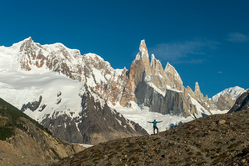 Mature backpacker stands on ridge with distant mountain summits, Fitzroy area, Patagonia
