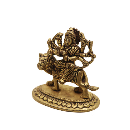 statue of goddess durga devi of hindu religion holding multiple weapons in her many arms, sitting on her lion, handcrafted with details in golden brass isolated in a white background