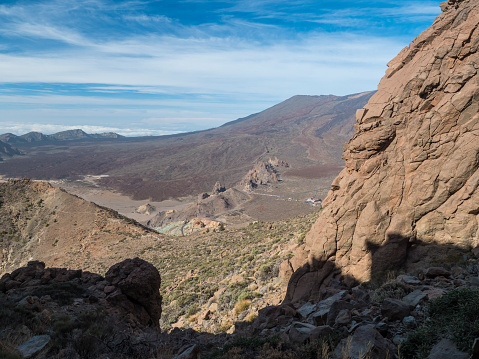 View on Los Roques de Garcia rock formation and slope of colorful volcano Pico del Teide from from top of Alto de Guajara mountain, blue sky, white clouds. Tenerife Canary island.