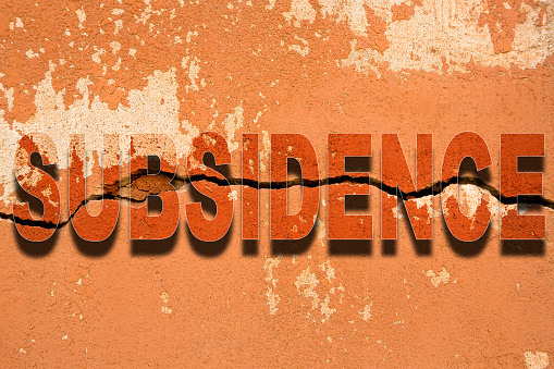 Building sinks into the ground due to subsidence phenomena - Deep horizontal crack in an old wall with damaged plaster - Building damaged due to structural failure, vertical movement or earthquake.