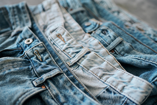 Multiple pairs of blue denim jeans stacked neatly on top of each other for display. Stock photo