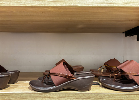 Trendy ladies sandals slippers on shelf in shop, display.