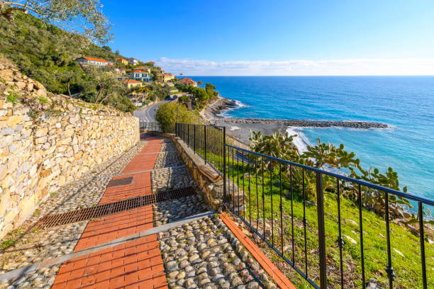 View of hillside homes and the Ligurian sea from the steep pedestrian coastal walkway to the hilltop medieval town of Cervo, Italy, in the Imperia province of the region of Liguria, along the Italian Riviera. vista de las casas en la ladera y el mar de liguria desde el empinado paseo peatonal costero hasta la ciudad medieval de cervo, italia, en la cima de la colina, en la provincia de imperia de la región de liguria, a lo largo de la riviera italiana.