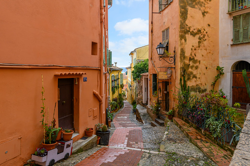 A picturesque narrow street in the medieval old town residential district in the Mediterranean city of Menton, France, along the Cote d'Azur French Riviera.