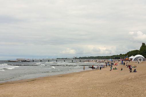 Kolobrzeg, Poland - June 26, 2016: Several unidentified holidaymakers are enjoying their leisure time on the Baltic Sea coast on an overcast day.