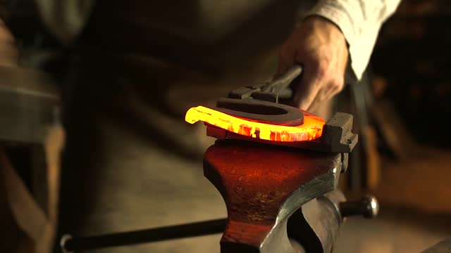 Blacksmith Bends a Hot Iron on a Special Mounting for Horseshoe Bending.