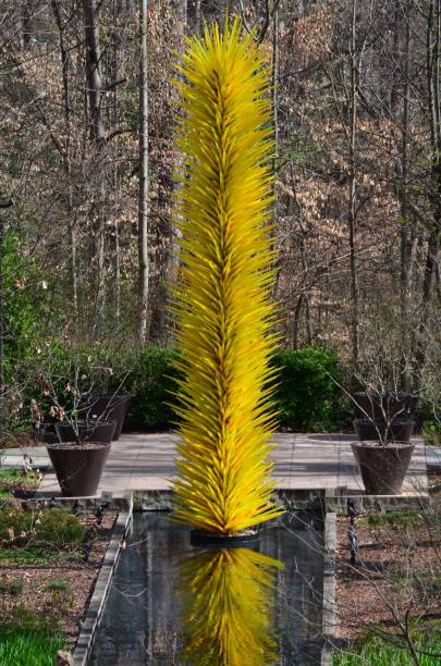 Yellow fountain with cascading water in front of lush trees