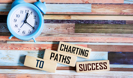 Charting paths to success quotes on wooden blocks and vintage background with clock