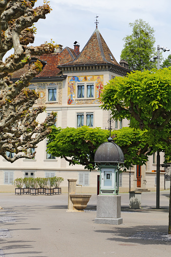 Rapperswil, Switzerland - 10 May 2016: The weather data column is located on a sidewalk next to the small fountain. The view is complemented by historic architecture and lots of greenery.