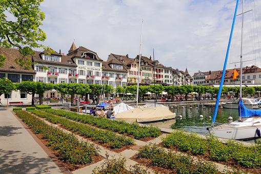 Rapperswil, Switzerland - May 10, 2016: A promenade along the lake with a view of the city, together with moored boats on the waters of the lake, creates a landscape inviting for a holiday.