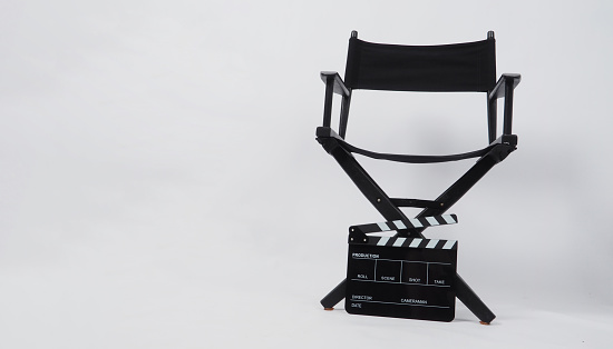 Black director chair and clapperboard put on floor with white background.