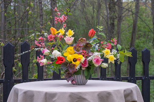 A floral arrangement of spring flowers on a table in the garden. Wedding table decor in spring.