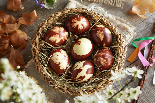 Brown Easter eggs dyed with onion peels with a pattern of fresh leaves in a basket