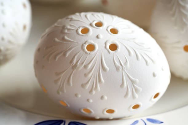 White Easter egg decorated with wax with drilled holes, closeup