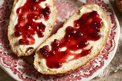 A slice of traditional Czech sweet Easter cake called mazanec with butter and cranberry marmalade on a red plate
