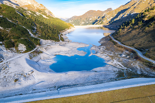 Dangerously low water levels in dam reservoir in the Dolomite mountains Italy during summer heat wave