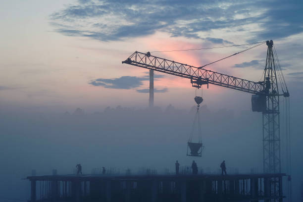 a construction site and a crane in the fog at sunset