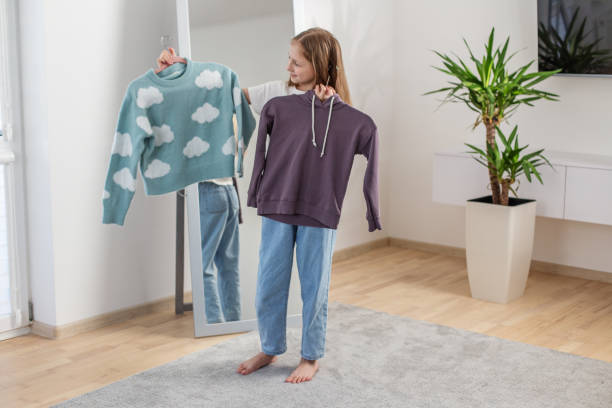 istock Child Girl Choosing Between Two Sweaters at Home. Morning preparation before school. 2144174183