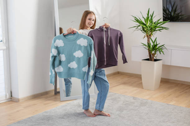 istock Child Choosing Between Two Sweaters at Home. Morning preparation before school. 2144174185
