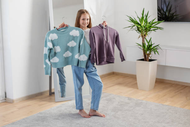 Child Choosing Between Two Sweaters at Home. Morning preparation before school.