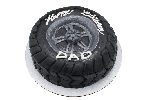 Happy birthday dad Modern designer chocolate cake in the shape of a black car rubber tire with dark fondant as the off road tread pattern. Isolated on white background top side view