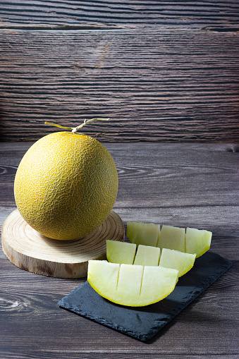 Galia melon slices on a wooden background.