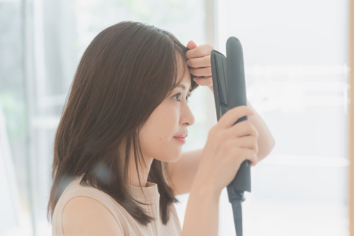 Young woman using a hair iron to set her hair