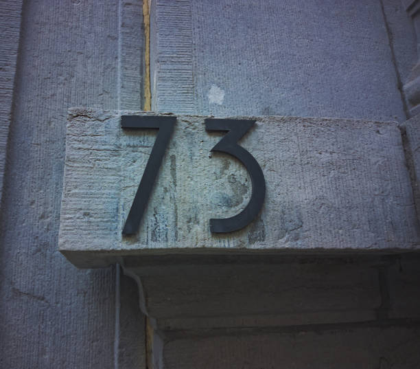 istock Number seventy three (73) on house. On a stone wall that has been exposed to the elements 2144384048