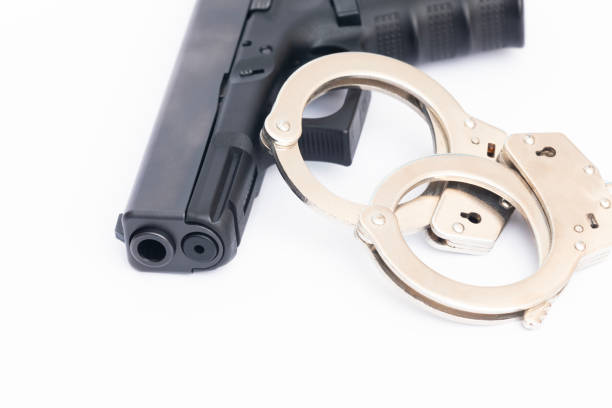 istock Crime concept. Hand gun weapon with handcuffs 2144431258