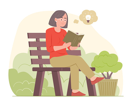 Senior woman sitting on wood bench in garden and reading a book
