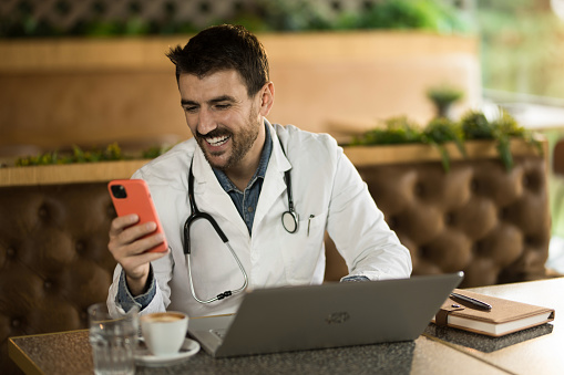 Young male healthcare worker using smart phone while working in a restaurant.