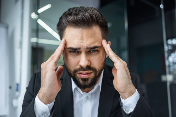 istock frustrated businessman suffering from headache migraine at workplace, massaging temples, feeling tired exhausted, chronic work stress 2144535919
