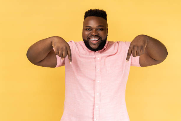 istock Man pointing down place for commercial idea, looking at camera with toothy smile. 2144546626