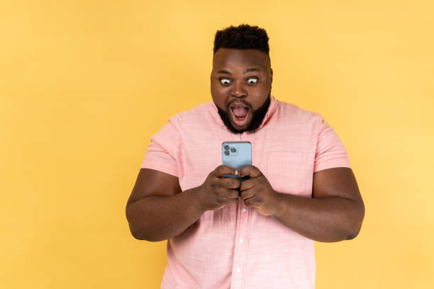 istock Man reading shocking post on social network using cell phone, looking at display with big eyes. 2144546631