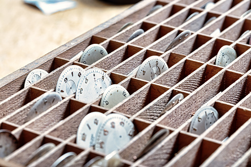 meticulous order of watch dials in compartments, each a frozen moment in the watchmaker's care