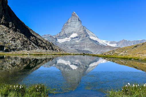 Serene summer landscape, the famous Matterhorn mountain in Zermatt, Switzerland, gently mirrors its grandeur in the calm waters of Riffelsee. Breathtaking alpine view. Beautiful landscape.