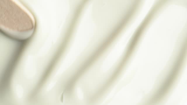 Moisturising creme swatch motion with spatula. Cosmetic texture of anti-cellulite cream for body, macro shot.
