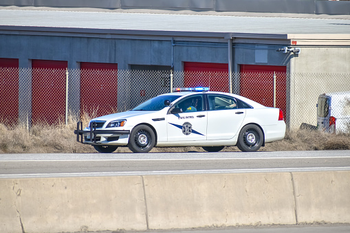 A Washington State Patrol Chevrolet Caprice Police vehicle parked on the side of the freeway while a State Trooper conducts a traffic stop.