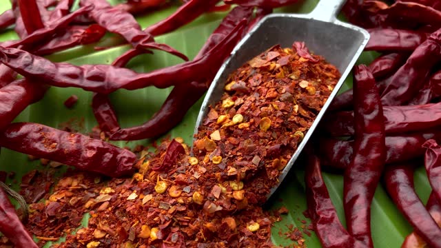 Dried and crushed red chili peppers on a fresh banana leaf background