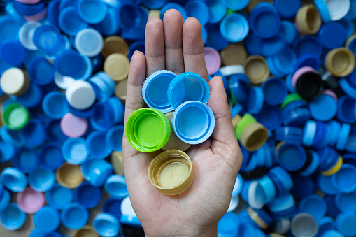woman hand holding plastic bottles caps for recycling to conserve the environment, Recycling, reuse, garbage disposal, save the world concpet.