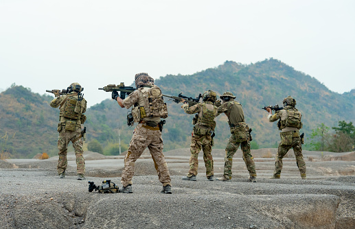 Side view group of military or soldiers stand with point gun to left side to the enemy in area of battlefiled or practice area.