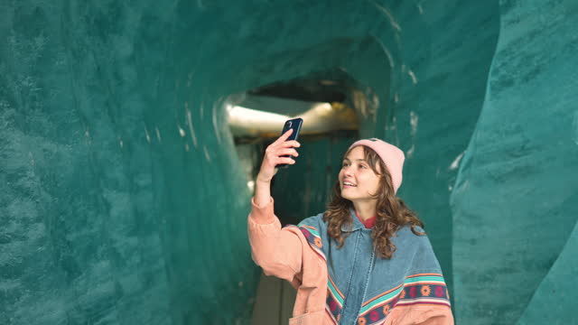 Woman photographing with smartphone in ice cave