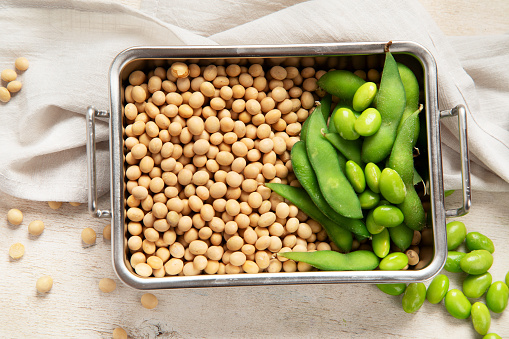 Soybeans on light cotton and wooden background. Vegan food concept. Top view