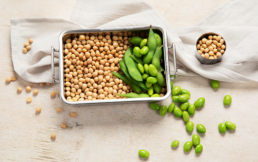 Soybeans on light cotton and wooden background. Vegan food concept. Top view